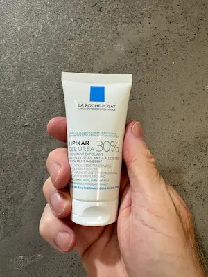 Holding a product tube of La Roche Posay Lipikar Urea Gel 30%.
