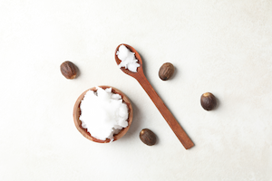 Raw shea nuts next to a spoon of unrefined shea butter.